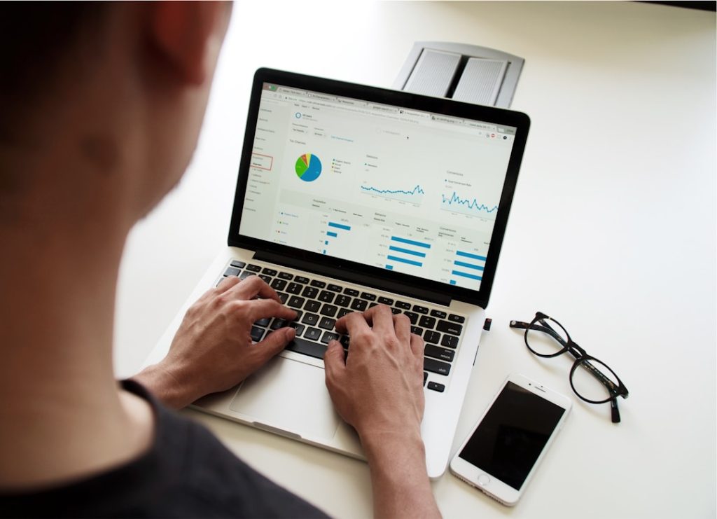 A person utilizing a laptop for financial management, with a graph visible on the screen for analysis.