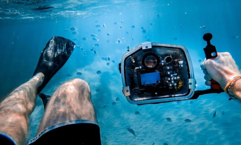 A man free diving in the sea while holding an action camera Photo by Jakob Owens on Unsplash